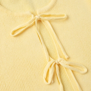 Close-up of light yellow ribbed knit top with delicate bow tie strings at the neckline