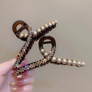 Elegant brown hair claws with pearls and rhinestones shown in a hand-held view