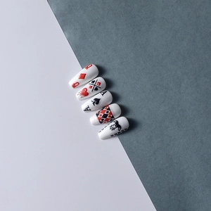 Macro detail of coffin-shaped nail tips featuring poker card Joker and Queen motifs