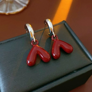 Detail of red heart-shaped enamel drop earrings with polished silver metal hoop