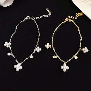 Detail of gold and silver bracelets featuring floral pearl charms and sparkling zircons