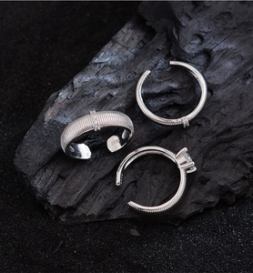 Detailed view of three silver S925 rings with striped texture and zircon on black charcoal