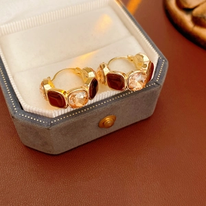 Detail view of gold hoop earrings with amber resin stones in a luxury jewelry box