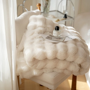 Creamy white plush faux rabbit fur blanket with luxury square grid texture on a chair