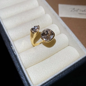 Detail of a gold double-headed open ring featuring pear and square cut cubic zirconia