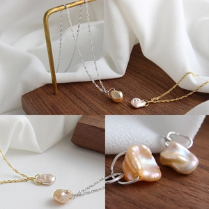 Macro detail of natural baroque pearl on fine gold and silver twisted wave chain