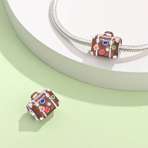 Detailed view of a vintage suitcase bead charm with colorful heart and star enamel patterns