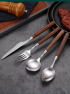 Detail of 304 stainless steel cutlery set with elegant walnut wood handles on stone surface