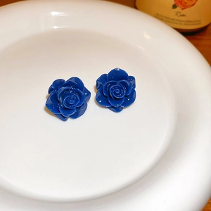 Vue détaillée de boucles d'oreilles rose bleu foncé avec tige en argent sur plat