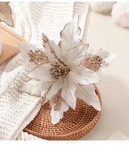 Gros plan sur un poinsettia artificiel blanc avec paillettes dorées sur set de table