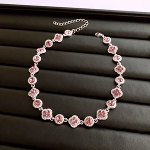Détail du collier trèfle avec cristaux roses et fermoir mousqueton sur plateau noir
