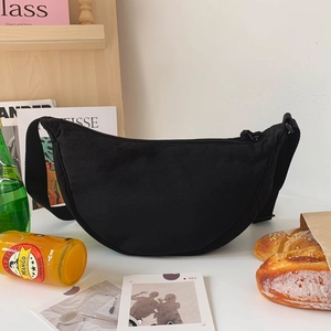 Modern black nylon crescent crossbody bag with adjustable strap in casual lifestyle setting