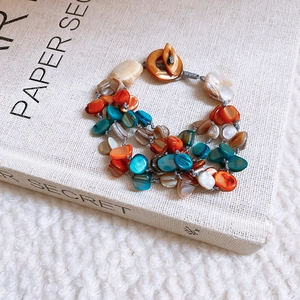 Detail of multi-strand beaded necklace with irregular shell beads and wooden toggle clasp
