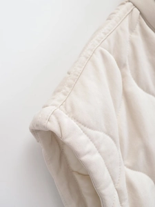 Detailed view of quilted beige vest showing premium fabric texture and neat stitching seams