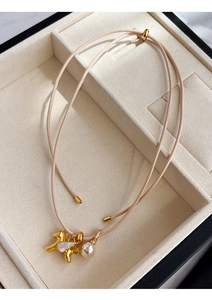 Détail d'un pendentif pégase doré avec nacre rose et une perle élégante sur cordon rose