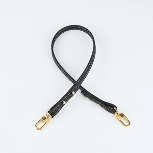 Macro detail of black lychee grain leather strap with gold buckle and white stitching