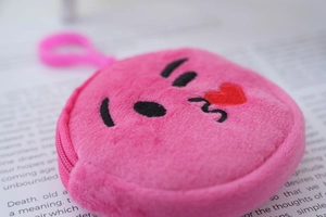 Close-up of pink plush coin purse with embroidered kiss emoji and plastic ring clip
