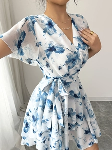 Abito da donna bianco con scollo a V e stampa floreale blu con gonna a balze elegante