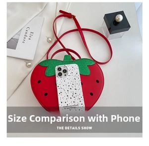 Detail of red strawberry bag with green leaves next to a phone for size comparison