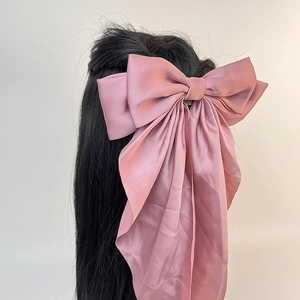 Vue détaillée d'une grande barrette à nœud en satin rose poudré avec de longs rubans