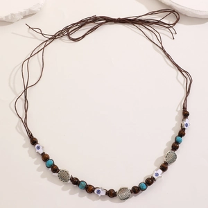 Detail of bohemian waist chain with Hamsa hand charm, turquoise beads and woven brown cord