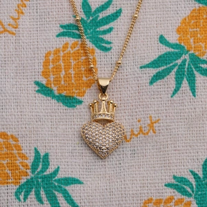 Golden crown heart necklace with clear cubic zirconia on a patterned background