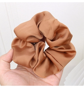 Detailed view of large caramel satin scrunchie with soft fabric folds and silky shine