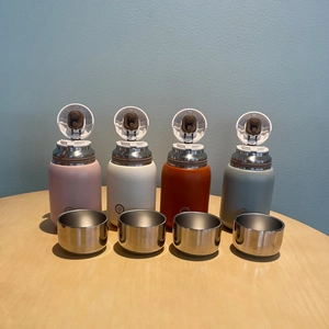 Detailed view of 316 stainless steel vacuum flasks in four colors on a wooden table