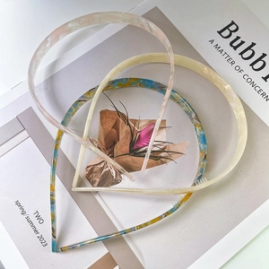 Minimalist acetate headbands in pink, cream, and tortoise patterns on a magazine