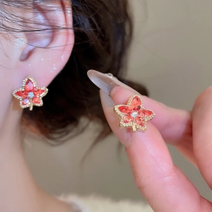 Detail of red maple leaf earring with gold metal frame and sparkling center zircons