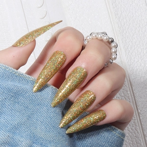 Long stiletto press-on nails with golden laser glitter finish worn by a model