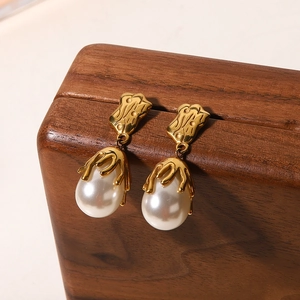 Macro shot of gold lava-textured metal drop earrings with white baroque pearls