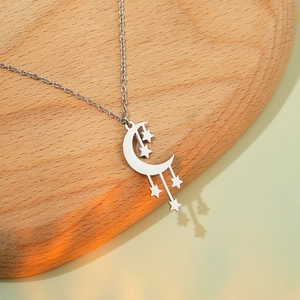 Close-up of silver crescent moon and stars pendant on O-chain necklace with soft shadows