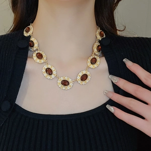 Close-up of vintage gold necklace featuring brown oval gemstones and crystal rhinestones