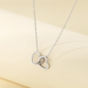 Detailed close-up of intertwined silver hollow heart pendants on a simple O-shaped chain