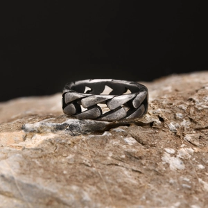 Gros plan détaillé d'une bague à chaîne cubaine en argent antique sur un rocher brut.