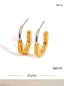 Detail of minimalist two-tone U-shaped stainless steel earrings with polished gold finish