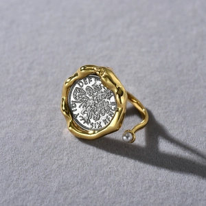 Detailed close-up of retro coin ring with golden finish and elegant white pearl accent