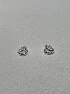 Detail of silver S925 geometric crossover hoop earrings with a polished metallic finish