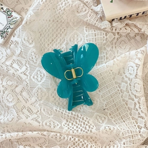 Détail de la pince à cheveux papillon bleu sarcelle avec ressort doré sur dentelle