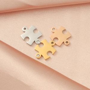 Detailed view of gold, silver, and rose gold puzzle pendants with small diamonds on pink silk