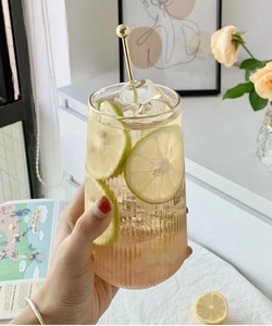 Close-up of textured ribbed glass cup with lemon water and golden stirring rod