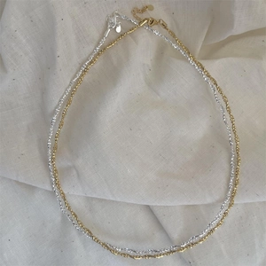 Detailed view of faceted silver and gold beaded necklaces with lobster clasps on fabric