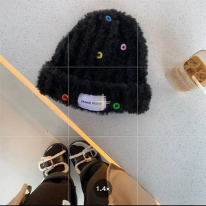 Detail of black plush knit beanie with colorful buttons and white woven patch label