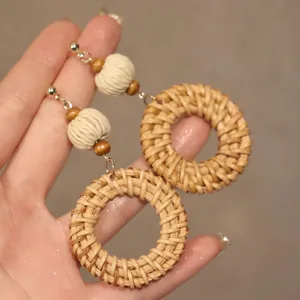 Detail of bohemian rattan hoop earrings with cream thread-wrapped beads and gold accents
