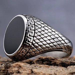 Detailed macro shot of vintage mens ring featuring black oval stone and Greek Key border