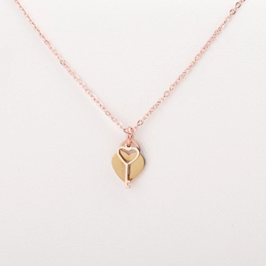 Macro detail of rose gold heart and key pendants on a premium white leather surface