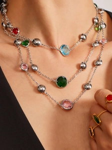 Close-up of geometric layered necklace with colorful glass stones and silver bead details