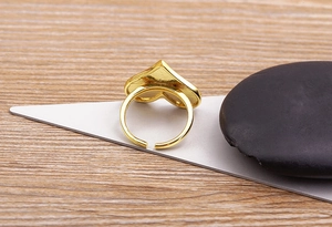 Detail of adjustable 18K gold plated heart ring featuring a polished metallic finish