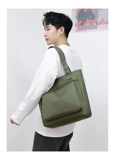 Man carrying a large army green nylon shoulder bag, side view on white background